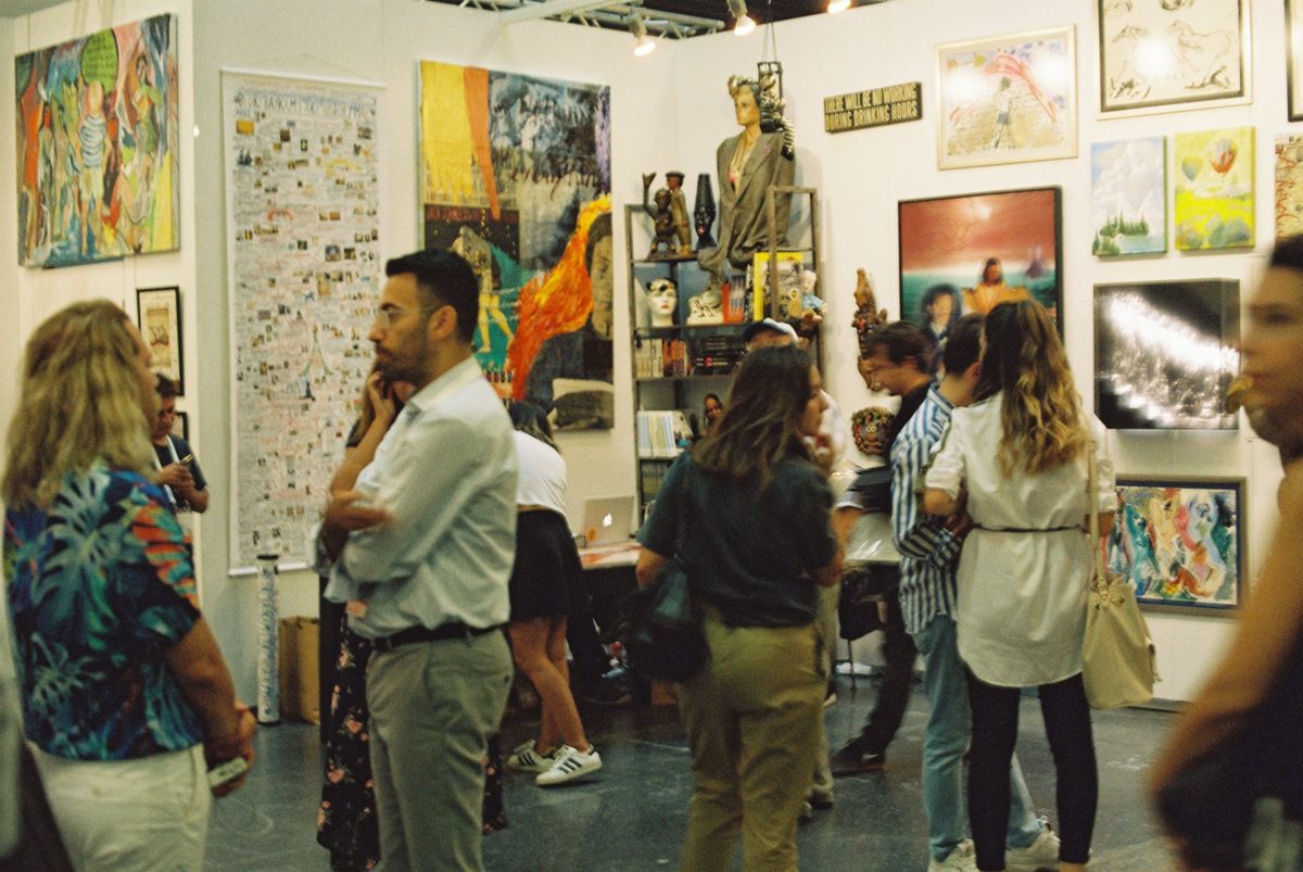 Adults exploring a lively art exhibition with varied paintings and sculptures